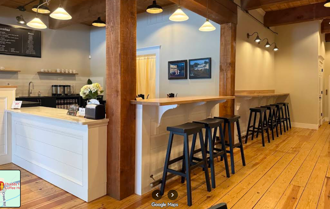 Interior of Chadds Ford Coffee House with timber beams, a long wooden bar and black stools